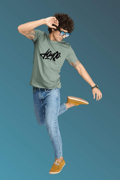 t-shirt featuring bold black stylized typography, worn with blue denim jeans and brown casual shoes. Set against a smooth blue gradient backdrop, the photo highlights modern streetwear style in a minimal, fashion-forward composition."